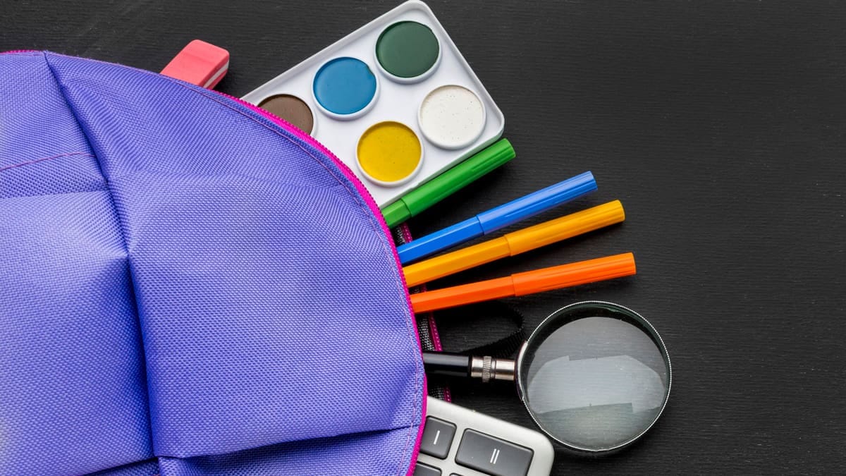 Carrinho de compras com material escolar ao lado de uma calculadora e uma lista com itens riscados