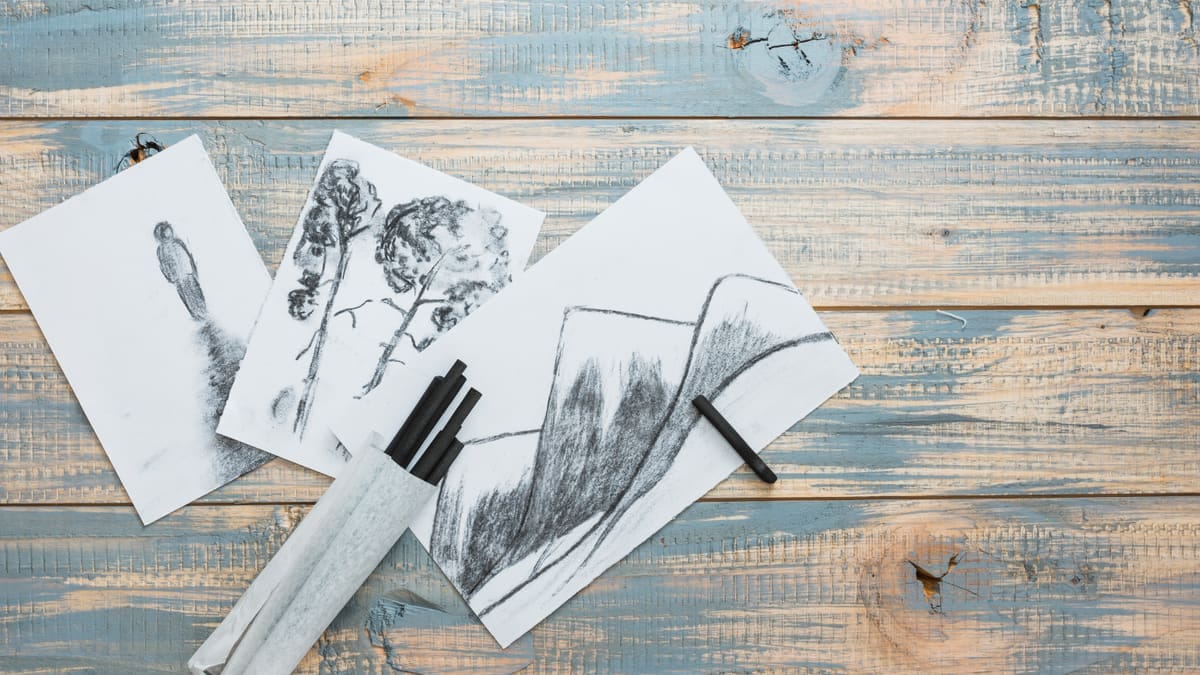 Lápis grafite de diferentes durezas enfileirados com amostras de traço de H a B em papel branco
