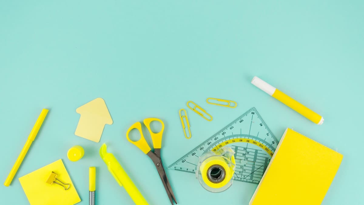 Lista de material escolar impressa sobre a mesa, com cadernos, lápis e uma calculadora ao lado
