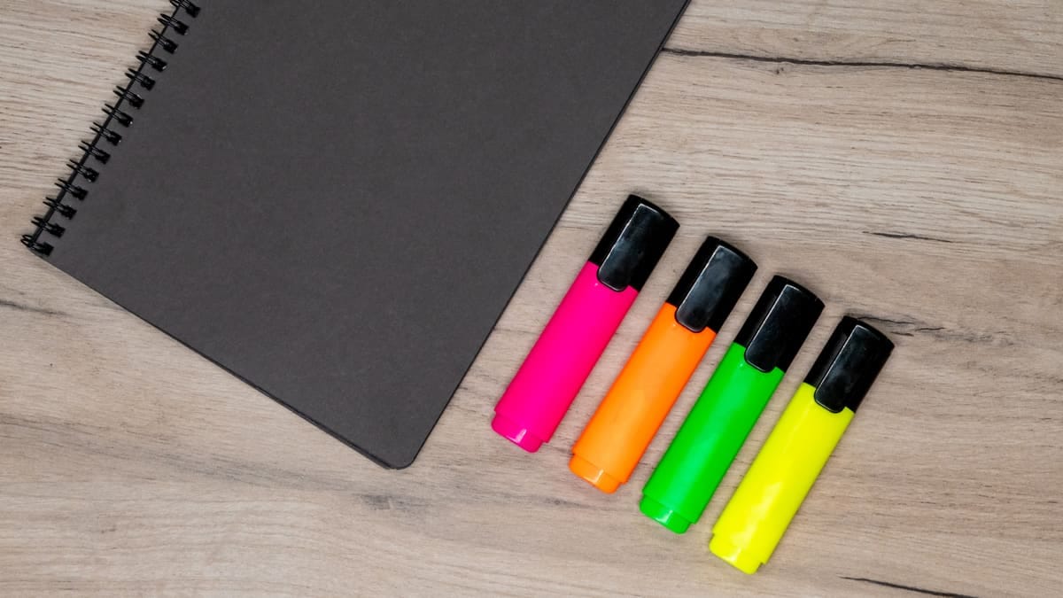 Seis marca-textos de cores diferentes com trechos grifados numa apostila impressa