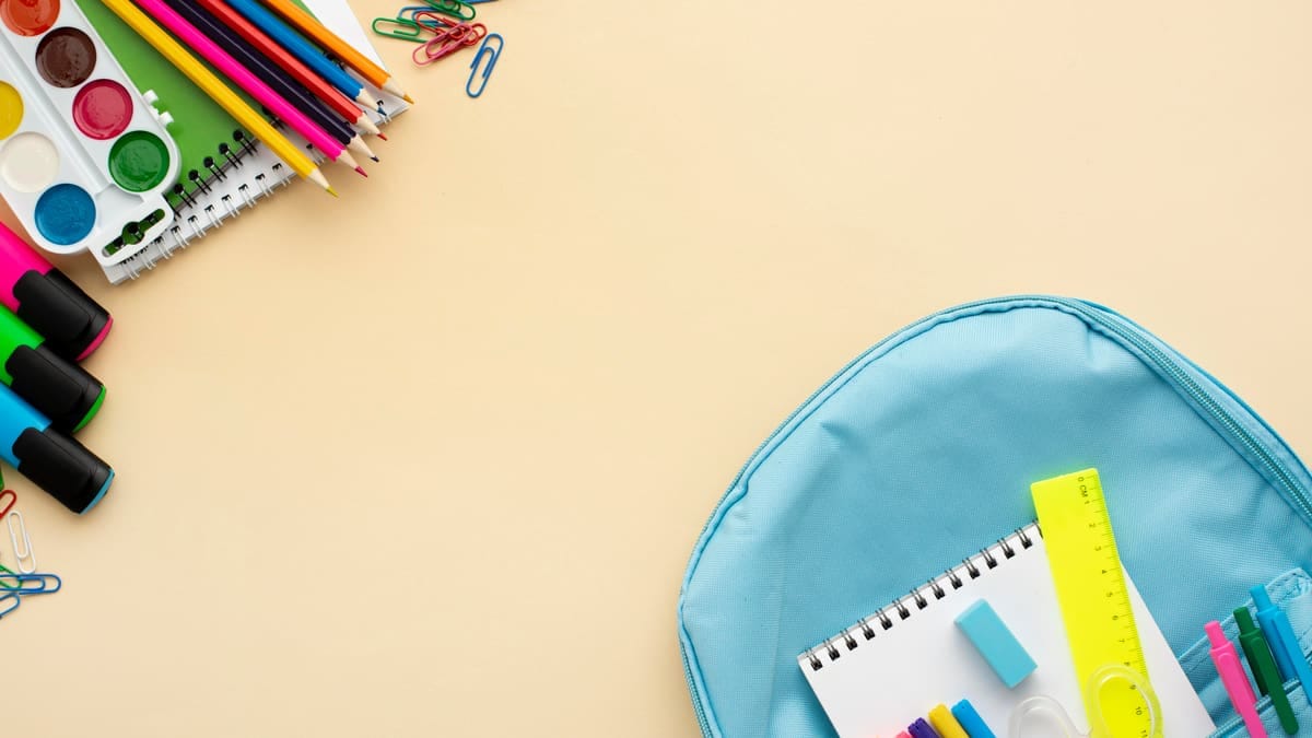 Seis mochilas escolares de cores variadas alinhadas em um banco de madeira, abertas para mostrar os compartimentos